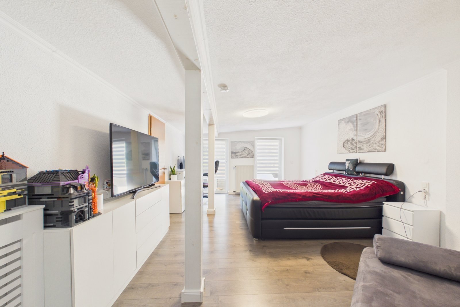 Schlafzimmer mit Laminatboden und Balkonzugang