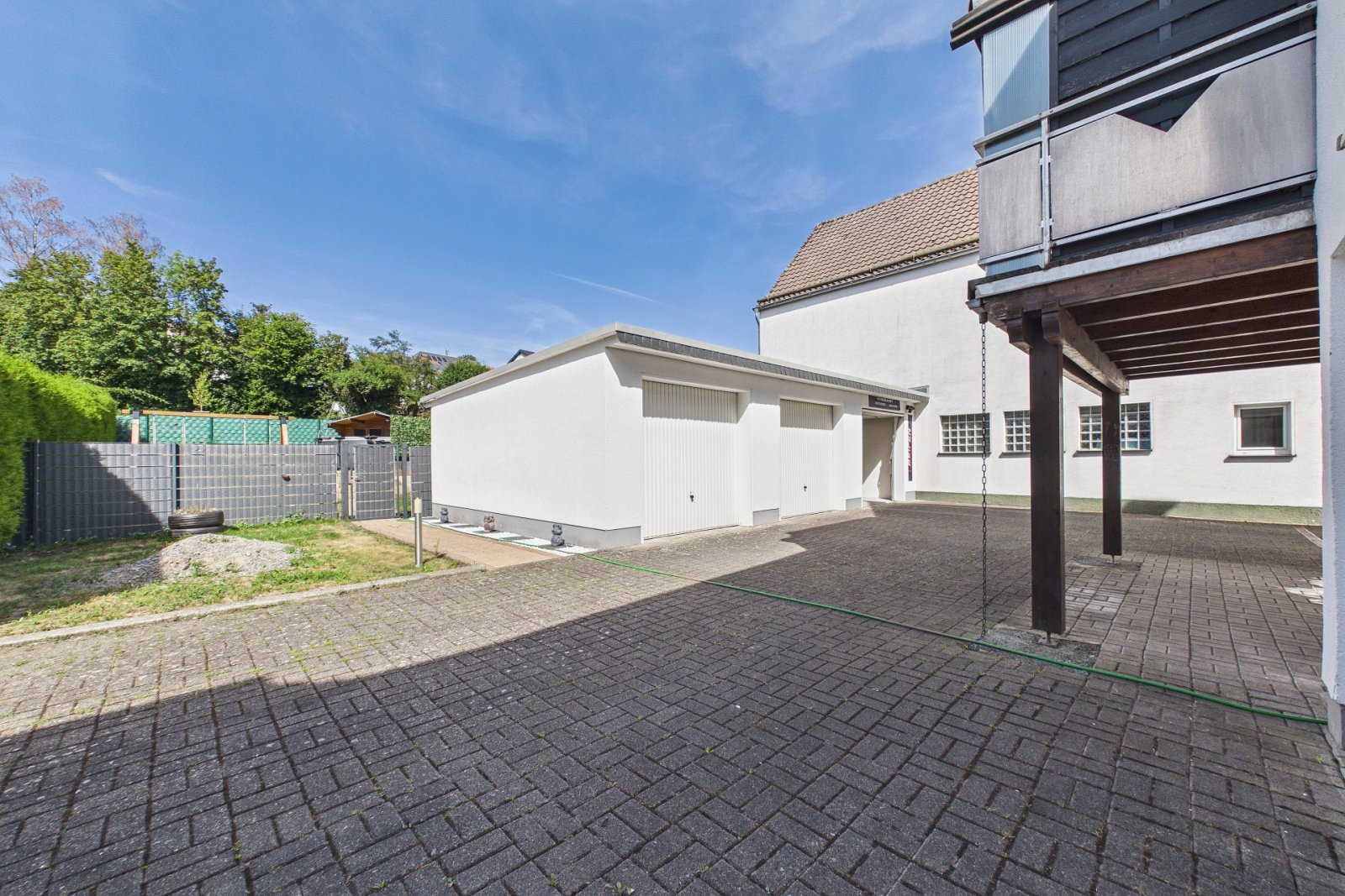 Gepflasterter Innenhof mit überdachtem Carport und Garage